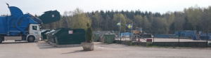 En blå lastbil tömmer en grön container.
