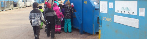 Barn bredvid en blå container.